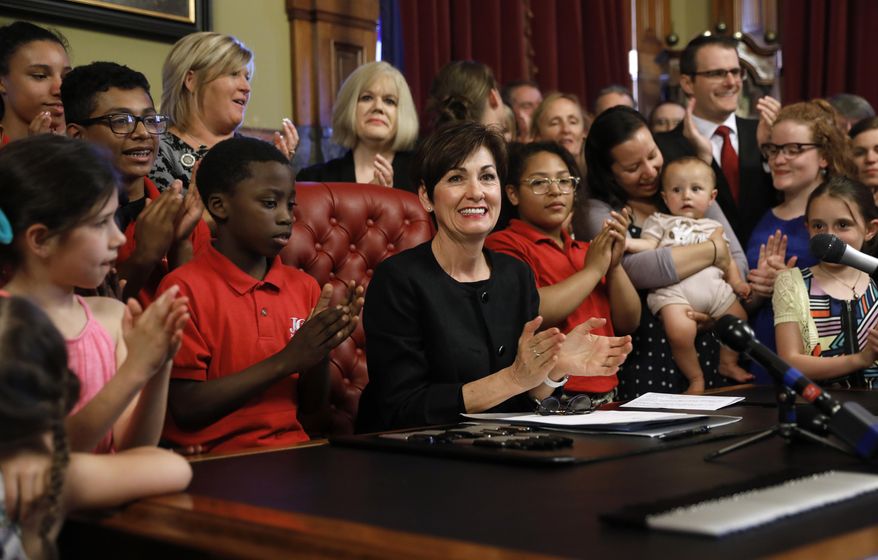 Iowa Gov. Kim Reynolds, center, reacts after signing a six-week abortion ban bill into law during a ceremony in her formal office, Friday, May 4, 2018, in Des Moines, Iowa. The bill gives Iowa the strictest abortion restrictions in the nation, setting the state up for a lengthy court challenge. (AP Photo/Charlie Neibergall) ** FILE **