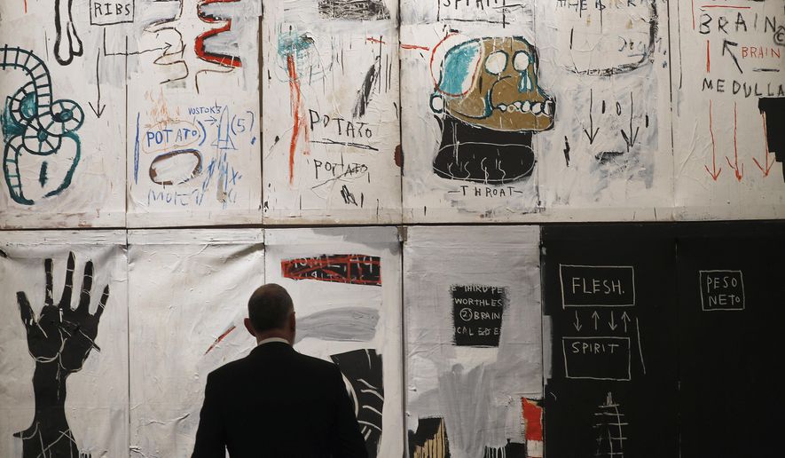 In this April 9, 2018, file photo, a man looks at the painting titled &quot;Flesh and Spirit&quot; by Jean-Michel Basquiat, in London. A Miami gallery next week will exhibit early works and auction digital files inspired by rare photographs of New York City street artist Basquiat, whose social commentary paintings on racism and power structures have risen astronomically in value since he died of a heroin overdose at age 27. (Associated Press) ** FILE **