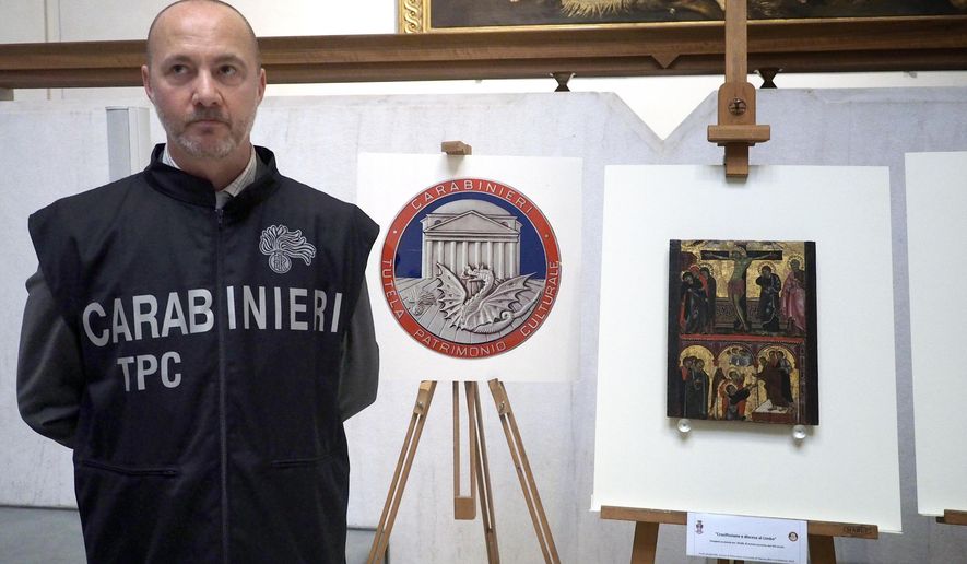 A Carabinieri (Italian paramilitary police) officer poses next to one of three stolen and recovered paintings, during a press conference in Bologna, Italy, Friday, May 4, 2018. Italy's art police say they've recovered three paintings stolen in recent months from three small Bologna-area museums after identifying the thief from surveillance videos. The most well-known piece was a 1363 portrait of St. Ambrose attributed to Giusto de' Menabuoi that was stolen in March from the National Pinacoteca of Bologna while it was open to the public. (Giorgio Benvenuti/ANSA via AP)