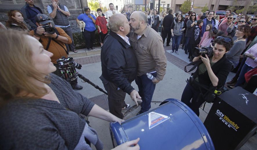 Mark Lindsay, left, and Tom Kerns kiss after mailing a resignation letter as Mormons gather for a mass resignation from the Church of Jesus Christ of Latter-day Saints Saturday, Nov. 14, 2015, in Salt Lake City. A day after the Mormon church stood behind its new rules targeting gay members and their children, while issuing clarifications, hundreds of gathered in Salt Lake City to protest their displeasure with the policy changes. The attendees joined together in renouncing their membership with The Church of Jesus Christ of Latter-day Saints. (AP Photo/Rick Bowmer)