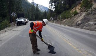 In this April 3, 2018 photo, a worker fills a pothole on Highway 50 near Kyburz, Calif. Propsition 69, the Gas Tax Amendment on the June ballot, will require gas tax money be spent on transportation. (AP Photo/Rich Pedroncelli)