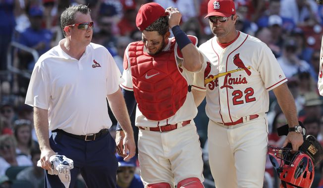 St. Louis Cardinals trainer Chris Conroy, left, and manager Mike Matheny (22) take catcher Yadier Molina back to the dugout after Molina was injured on a pitch during the ninth inning of a baseball game against the Chicago Cubs, Saturday, May 5, 2018, in St. Louis. (AP Photo/Charles Rex Arbogast)