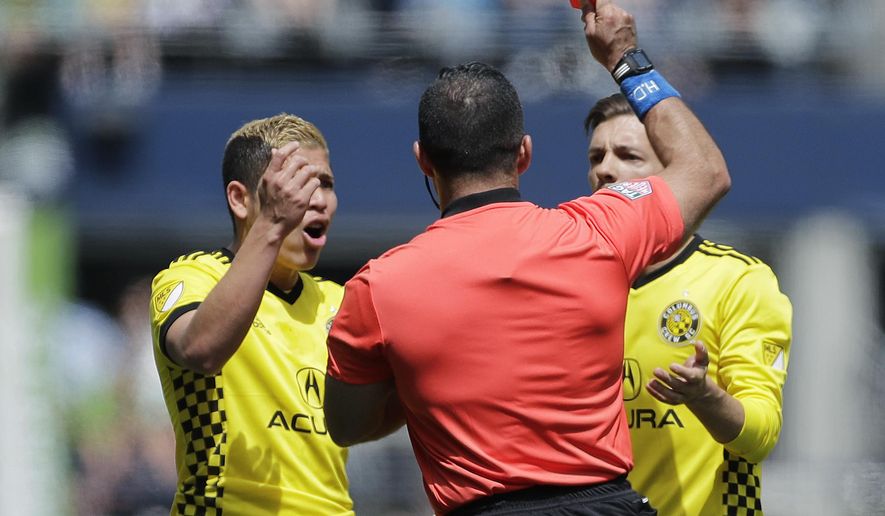 Columbus Crew midfielder Pedro Santos, right, is given a red card by referee Hilario Grajeda, center, as Crew midfielder Cristian Martinez, left, reacts after Santos made contact with the face of Seattle Sounders midfielder Alex Roldan in the first half of an MLS soccer match, Saturday, May 5, 2018, in Seattle. (AP Photo/Ted S. Warren)