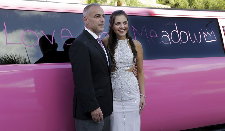 In this May 5, 2018 photo, Andrew Pollack father of Meadow Pollack poses with his daughter's best friend Carley Ogozaly next to a pink limousine with messages to honor her written by friends before heading to the prom in Parkland, Fla. Meadow Pollack was one of the four Florida high school seniors slain in a mass shooting honored by classmates celebrating their senior prom. (Pedro Portal/Miami Herald via AP)