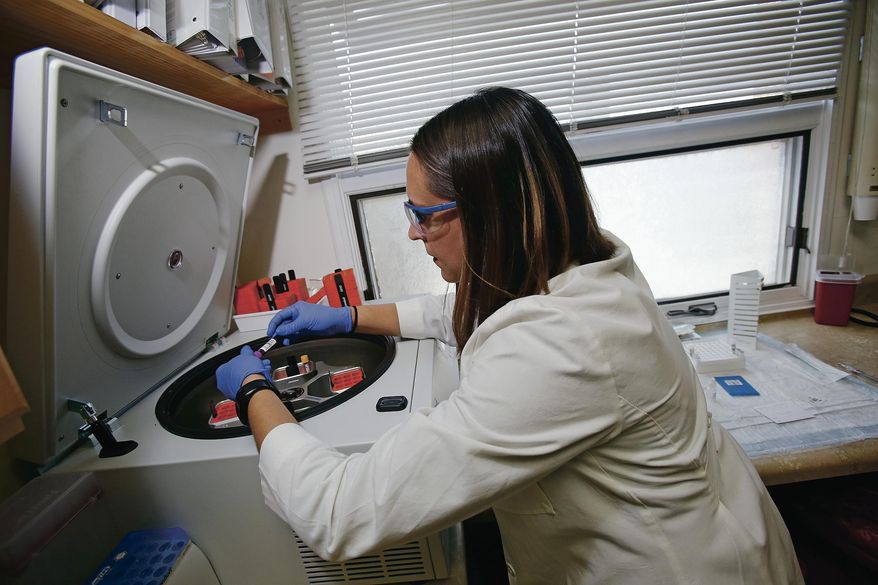 In this Wednesday, April 25, 2018 file photo, Tamara Flys, director of research at Southwest Care in Santa Fe, N.M., places a patient's blood sample in a centrifuge to prepare the blood to be sent out for testing. (Luis Sánchez Saturno/Santa Fe New Mexican via AP)