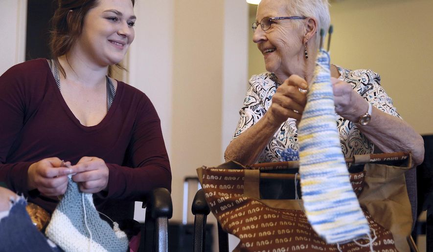 In a Monday, April 30, 2018 photo, Barker Creek Community School student Paige Harkness, 18, left, looks at the knitting of CRISTA Shores Senior Living resident Arlene Graff, in Silverdale Wash. Barker Creek Community School has a popular Knitting Club/Creative Fiber Arts Class and they have been learning to knit from two local volunteers they affectionately call "Grandma Bev" and "Grandma Joss." (Larry Steagall/Kitsap Sun via AP)