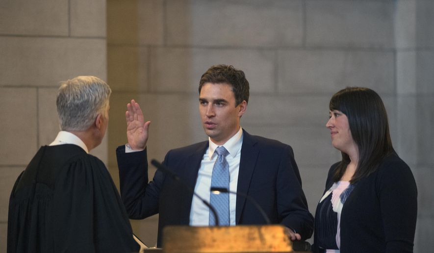 United States Supreme Court Justice Neil Gorsuch, left, swears in Jonathan Papik, center, as Rachel Papik stands by her husband's side Monday, May 7, 2018, in the Warner legislative chamber at the state Capitol in Lincoln, Neb. Justice Gorsuch administered the oath to Papik, the newest member of the Nebraska Supreme Court. (Kayla Wolf/Lincoln Journal Star via AP)