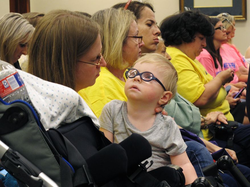 Kathryne Hart sits in the Senate Finance Committee with her 2-year-old son Carter after telling senators about her concerns about budget cuts proposed for the upcoming financial year, on Monday, May 7, 2018, in Baton Rouge, La. (AP Photo/Melinda Deslatte)