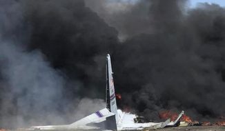 FILE - In this May 2, 2018 file photo, flames and smoke rise from an Air National Guard C-130 cargo plane after it crashed near Savannah, Ga. Recordings of 911 calls made moments after the large military plane crashed in Georgia show rattled motorists describing the aircraft plunging nose-first into the blacktop of a highway. One caller tells an emergency operator: “It just fell out of the sky and it&#39;s on fire right now.” Nine airmen from the Puerto Rico National Guard died.  (James Lavine via AP, File)