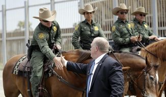 Immigration and Customs Enforcement Deputy Director Thomas Homan, front, shakes hands with mounted Border Patrol agents during a news conference along the border Monday, May 7, 2018, in San Diego. (AP Photo/Gregory Bull)