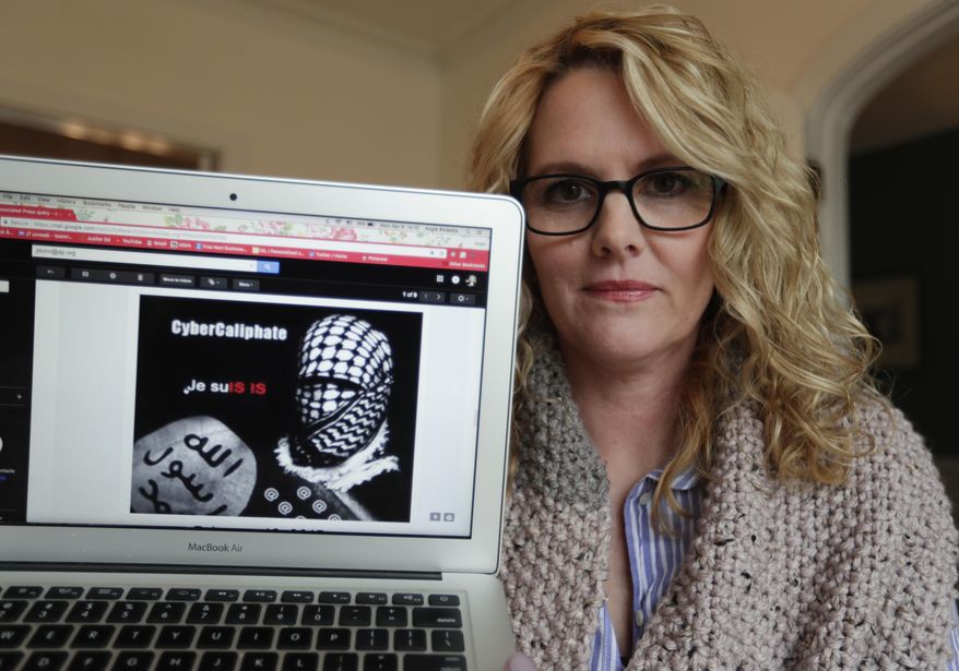 In this Monday, April 9, 2018, photo, Angela Ricketts poses with a screen shot of a message she received from a group claiming to be Islamic State supporters, in Bloomington, Ind. Russian spies masqueraded as Islamic State supporters to threaten vocal spouses of U.S. military personnel, including Ricketts, The Associated Press has found. (AP Photo/Michael Conroy)