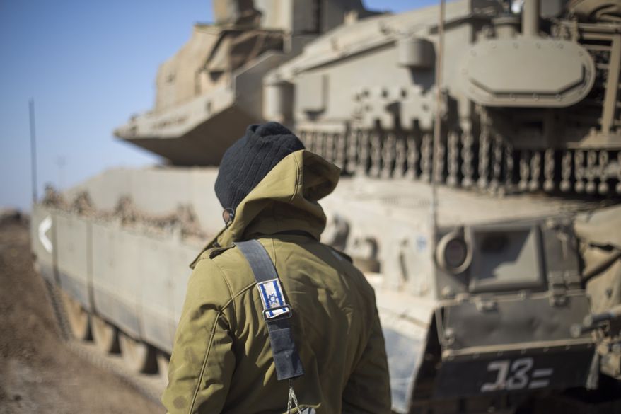 An Israeli soldier stand by a tank near the border with Syria in the Israeli-controlled Golan Heights, Monday, Nov. 28, 2016. The Israeli military says it has carried out an air strike in Syria on a building used by Islamic State militants to attack Israeli forces. The overnight air strike Monday targeted an abandoned United Nations building that Israel says was used as a base by the militants. (AP Photo/Ariel Schalit)