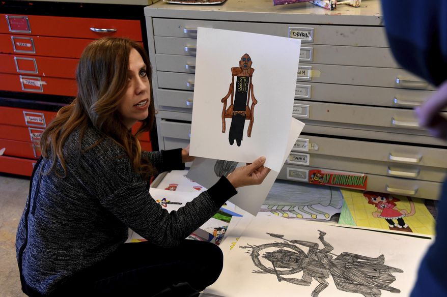 ADVANCE FOR WEEKEND EDITIONS, MAY 12-13 - In this April 19, 2018 photo, A.J. Paron-Wildes, left, looks through the art work of her son, Devin Wildes, as she talks with him before he starts his art projects for the day at Interact Center for Visual and Performing Arts in St. Paul. Devin, who has a severe form of autism, rarely speaks; But when he was 5 years old, Wildes learned to draw. "When he started doing art, the one thing that we noticed was that he was really in his own skin," said Paron-Wildes. (Jean Pieri/Pioneer Press via AP)