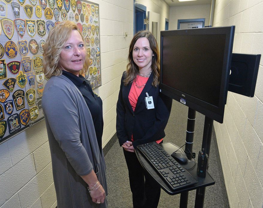 ADVANCE FOR WEEKEND EDITIONS, MAY 12-13 - In this May 1, 2018 photo, registered nurse Stacey Petruso, left, and Dr. Keelin Garvey show off a portable computer with built-in webcam at the Erie County Prison in Erie, Pa., during a meeting with corrections and mental health officials at the jail. Petruso is a nurse with Stairways Behavioral Health. Garvey is a forensic psychiatrist who will offer services at the jail through telepsychiatry. Once the program is up and running, Garvey will consult with inmates and staff via video link from Rhode Island, where she is based. (Christopher Millette/Erie Times-News via AP)