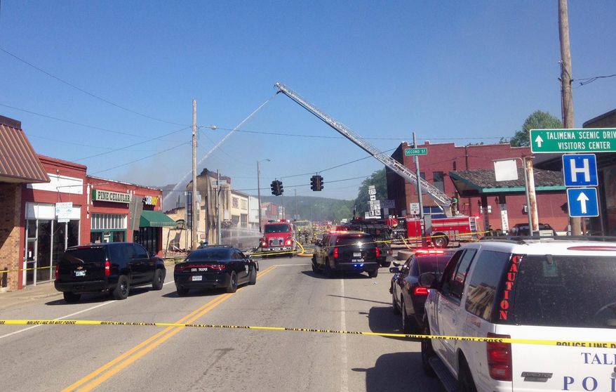 Emergency vehicles block a street in downtown Talihina, Okla., Friday, May 11, 2018, after a large fire began when search warrants were being served in the small Oklahoma town. Four Oklahoma troopers were struck by gunfire or shrapnel while serving a warrant early Friday at a man's home that may have been booby-trapped to spark a large fire, authorities said. (Max Bryan/The Southwest Times Record via AP)