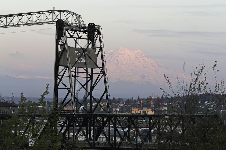 In this May 7, 2018 photo, Mount Rainier is seen at dusk behind the Murray Morgan Bridge in downtown Tacoma, Wash. The eruption of the Kilauea volcano in Hawaii has geologic experts along the West Coast warily eyeing the volcanic peaks in Washington, Oregon and California, including Rainier, that are part of the Pacific Ocean's ring of fire. (AP Photo/Ted S. Warren)