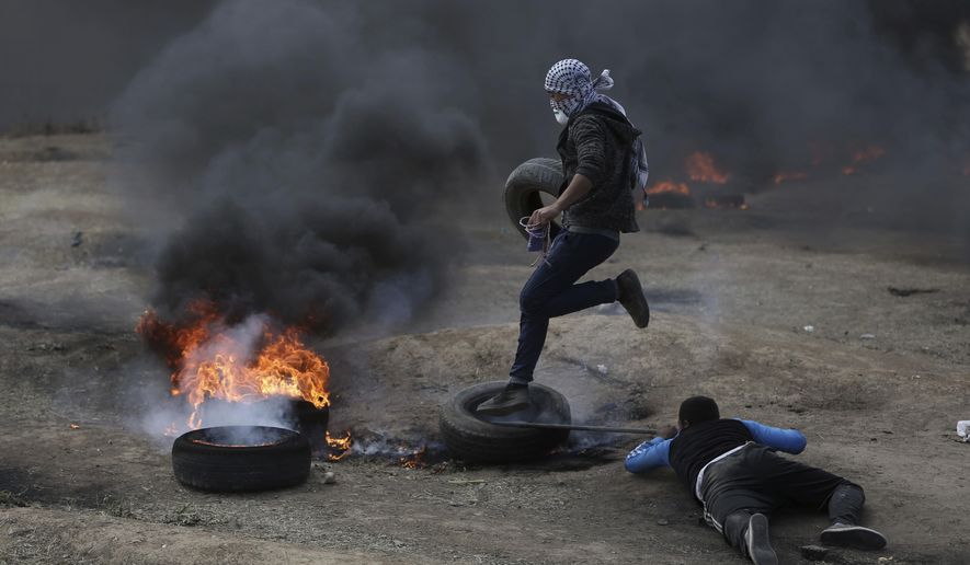 Palestinian protesters burn tires during a protest on the Gaza Strip&#39;s border with Israel, Monday, May 14, 2018. Thousands of Palestinians are protesting near Gaza&#39;s border with Israel, as Israel prepared for the festive inauguration of a new U.S. Embassy in contested Jerusalem. (AP Photo/Khalil Hamra)