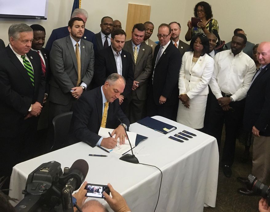 FILE - In this June 15, 2017, file photo, a bipartisan group of lawmakers surround Louisiana Gov. John Bel Edwards as he signs 10 criminal justice bills into law during a ceremony in Baton Rouge, La. Months after a heavily hyped overhaul of Louisiana’s criminal justice codes, lawmakers have introduced a flurry of proposals to walk back some of the changes. (AP Photo/R.J. Rico, File)