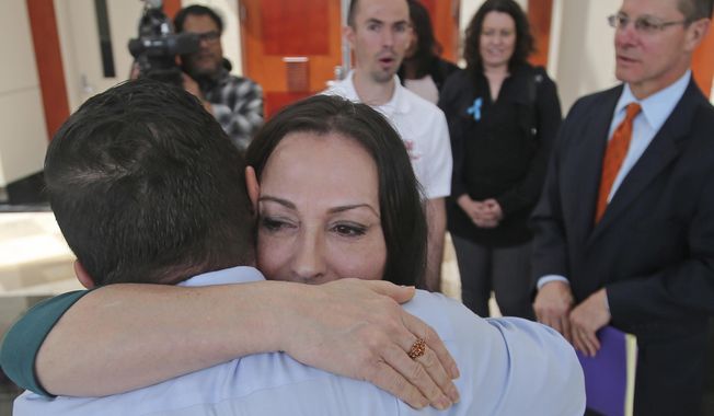Terry Mitchell receives a hug from her husband Greg following a hearing, which is a key test of a law aimed at allowing people who say they were sexually abused to sue decades later, at the Utah Supreme Court Monday, May 14, 2018, in Salt Lake City, The Utah Supreme Court heard arguments in a lawsuit against a former federal judge accused of sexually assaulting a teenage witness when he was a prosecutor handling a white supremacist serial-killer trial. The suit was filed by Mitchell who says Richard W. Roberts, who went on to be a federal judge, abused her in Utah in 1981. (AP Photo/Rick Bowmer)