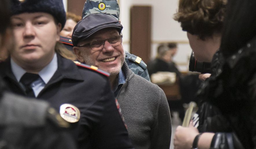 In this photo taken on Tuesday, Jan. 16, 2018, Alexei Malobrodsky, center, the former director of Moscow's Gogol Center, who was arrested in June of 2017, on charges of embezzling public funds allocated for a theater production is escorted to the court room in Moscow, Russia. A Russian theater manager accused of embezzlement has been released from prison following public outrage that he remained in detention after a health emergency. (AP Photo/Alexander Zemlianichenko)