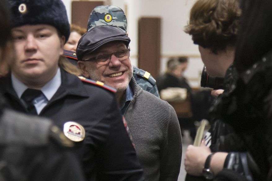 In this photo taken on Tuesday, Jan. 16, 2018, Alexei Malobrodsky, center, the former director of Moscow's Gogol Center, who was arrested in June of 2017, on charges of embezzling public funds allocated for a theater production is escorted to the court room in Moscow, Russia. A Russian theater manager accused of embezzlement has been released from prison following public outrage that he remained in detention after a health emergency. (AP Photo/Alexander Zemlianichenko)