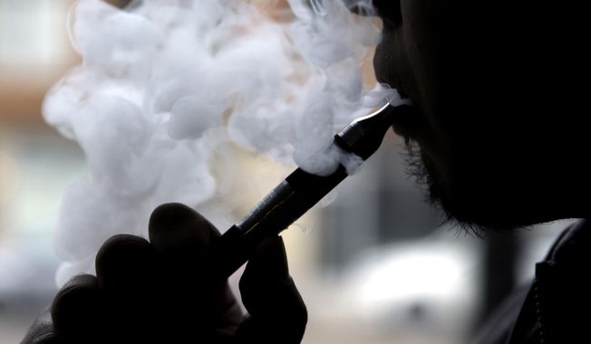 In this April 23, 2014, photo, a man smokes an electronic cigarette in Chicago. A study released on Tuesday, May 15, 2018 found that one in seven U.S. adults have tried e-cigarettes, an increase in recent years offset by a small decline in the number currently using the devices. (AP Photo/Nam Y. Huh) **FILE**