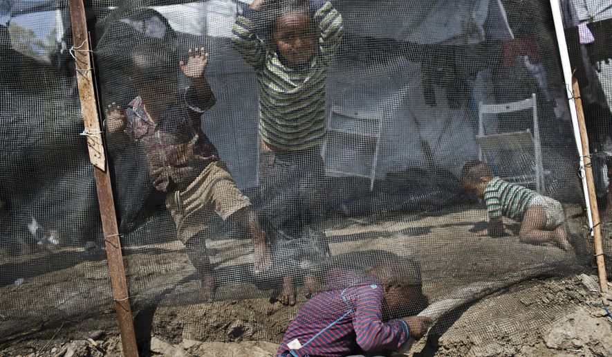 In this Tuesday, May 2, 2018 photo Syrian children play outside their family tent at a makeshift camp outside Moria on the northeastern Aegean island of Lesbos, Greece. Doctors at a health clinic at the site say they have to turn sick children away every day due to the scale of the treatment required. (AP Photo/Petros Giannakouris)