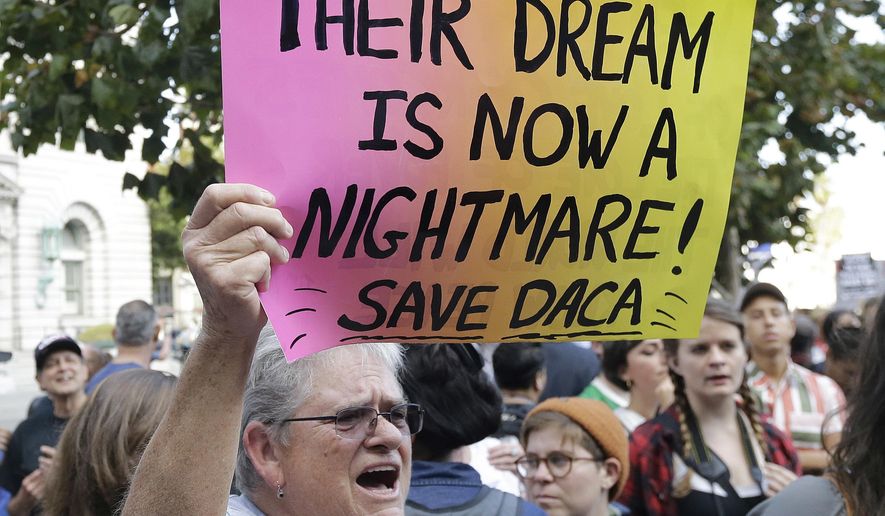 In this Sept. 15, 2017, file photo, Judy Weatherly, a supporter of the Deferred Action for Childhood Arrivals (DACA) holds up a sign during a protest outside of the Federal Building in San Francisco. (AP Photo/Jeff Chiu, File)