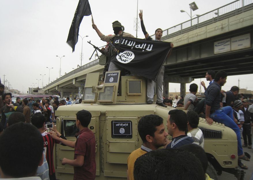 Islamic State group militants hold up their flag as they patrol in a commandeered Iraqi military vehicle in Fallujah, 40 miles (65 kilometers) west of Baghdad, on March 30, 2014. (Associated Press) **FILE**