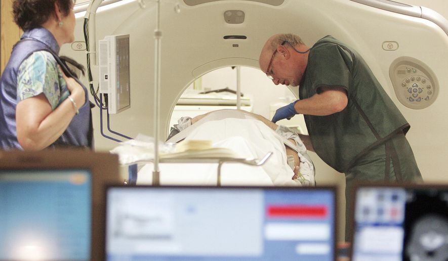 FILE - In this June 3, 2010, file photo, Dr. Steven Birnbaum works with a patient in a CT scanner at Southern New Hampshire Medical Center in Nashua, N.H. According to a study released on Wednesday, May 16, 2018, less than 2 percent of eligible current and former smokers have sought free lung cancer screening, five years after government and private insurers started paying for it. (AP Photo/Jim Cole, File)