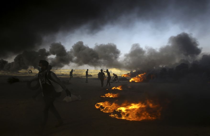 FILE - In this Tuesday, May 15, 2018 file photo, Palestinian protesters burn tires at the Gaza Strip's border with Israel, east of Khan Younis. The aftershocks of the U.S. Embassy move to Jerusalem and bloodshed on the Gaza border are shaking up the region, including the relationship between Palestinian President Mahmoud Abbas and former his negotiating partners, Israel and the U.S. Seething over a perceived U.S. betrayal on Jerusalem, Abbas is preparing to pursue what has been called his doomsday weapon, a war crimes complaint against Israel at the International Criminal Court. (AP Photo/Adel Hana, File)