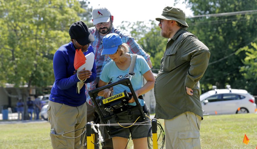 Davette Gadison, left, bio archeology grad student at Tulane University, and Andy Schroll, archeology grad student, behind, look over data with Dr. Cynthia Ebinger and Dr. Ryan Gallacher, in Thibodaux, La., Thursday, May 17, 2018. They are using ground penetrating radar equipment on a piece of land that may hold a mass grave from a Reconstruction-era racial massacre in Louisiana. The results could indicate whether digging would likely turn up a mass grave where white mobs are said to have dumped the bodies of African-Americans they killed in 1887. (AP Photo/Gerald Herbert)