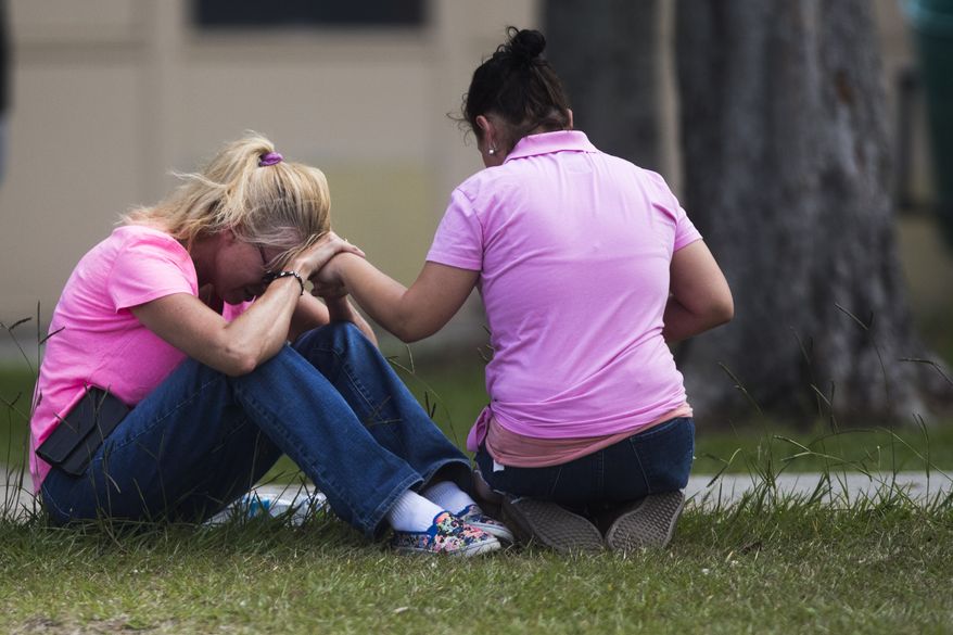 Two women pray outside the family reunification site following a shooting at Santa Fe High School on Friday, May 18, 2018, in Santa Fe, Texas.  (Marie D. De Jesus /Houston Chronicle via AP)