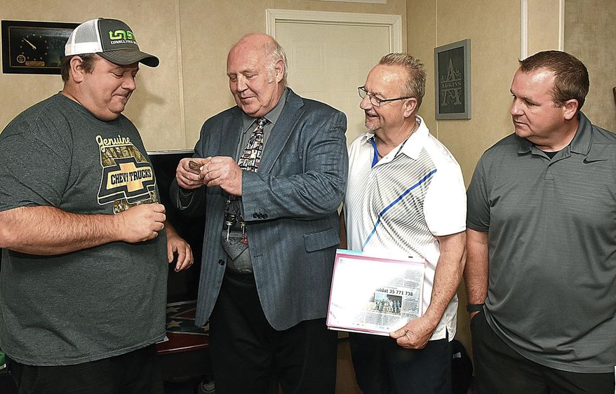 Mike Adkins Jr., left, receives his grandfather Wallace Adkins' dog tag from Kirk Fechter, the safety director of Fort Meade on May 14, 2018 in Scarbro, W. Va. The dog tag lost in Europe during World War II was found by a French soldier in 2013 and returned to the family. (Rick Barbero/The Register-Herald via AP)