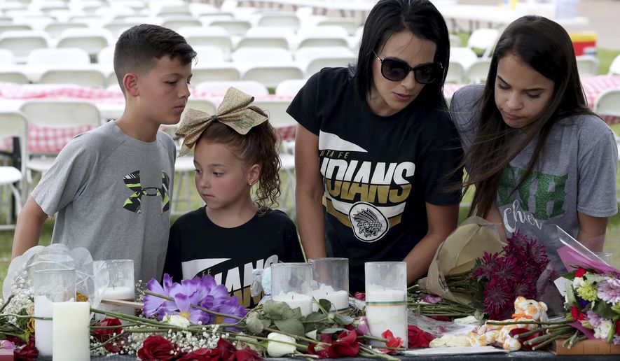 April Salinas, second from right, her daughters Meah, 13, and Macee, 6, and Jeramiah Kelley read notes left at memorial behind Texas First Bank, Saturday, May 19, 2018 in Santa Fe, Texas. A gunman opened fire inside the school Friday, May 18, 2018, killing several people. (Jennifer Reynolds/The Galveston County Daily News via AP)