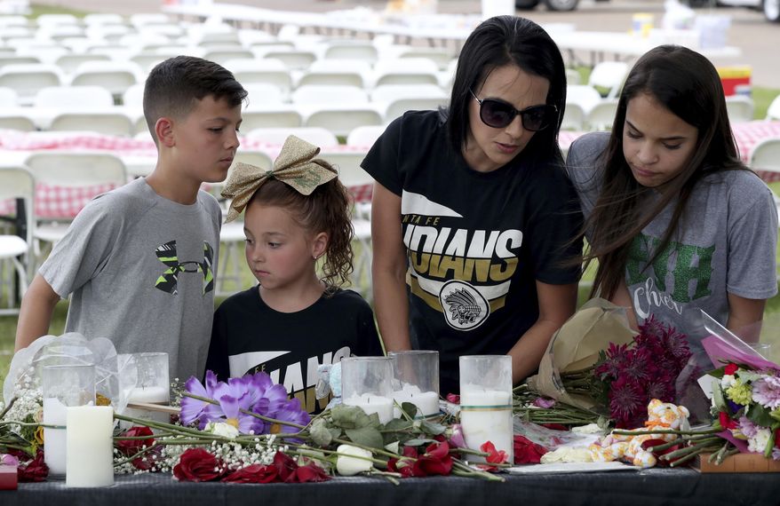 April Salinas, second from right, her daughters Meah, 13, and Macee, 6, and Jeramiah Kelley read notes left at memorial behind Texas First Bank, Saturday, May 19, 2018 in Santa Fe, Texas. A gunman opened fire inside the school Friday, May 18, 2018, killing several people. (Jennifer Reynolds/The Galveston County Daily News via AP)