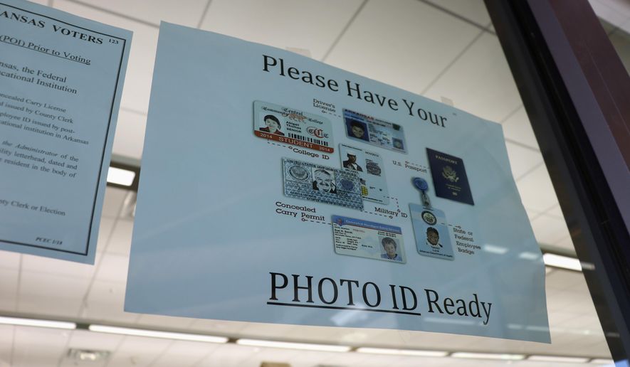 In this May 7, 2018, photo, a sign is posted above the check-in station for an early voting precinct at the Roosevelt Thompson Library in Little Rock, Ark., warning voters that they will be asked to show an identification card. Democratic and Republican voters on Tuesday, May 22, 2018, will choose nominees for the November general election, and all voters are eligible to vote in non-partisan court and prosecuting attorney races. (AP Photo/Kelly P. Kissel)