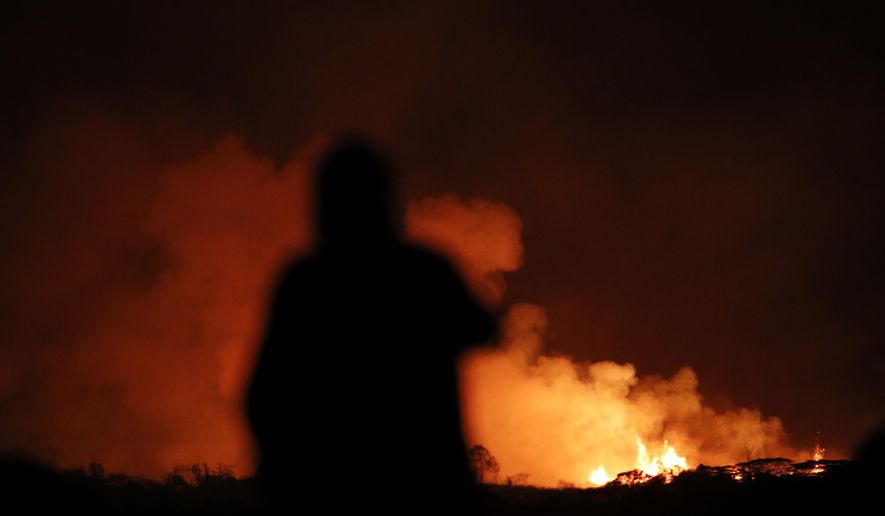A man photographs lava erupting from from a fissure near Pahoa, Hawaii Saturday, May 19, 2018. Two fissures that opened up in a rural Hawaii community have merged to produce faster and more fluid lava. Scientists say the characteristics of lava oozing from fissures in the ground has changed significantly as new magma mixes with decades-old stored lava.(AP Photo/Jae C. Hong)