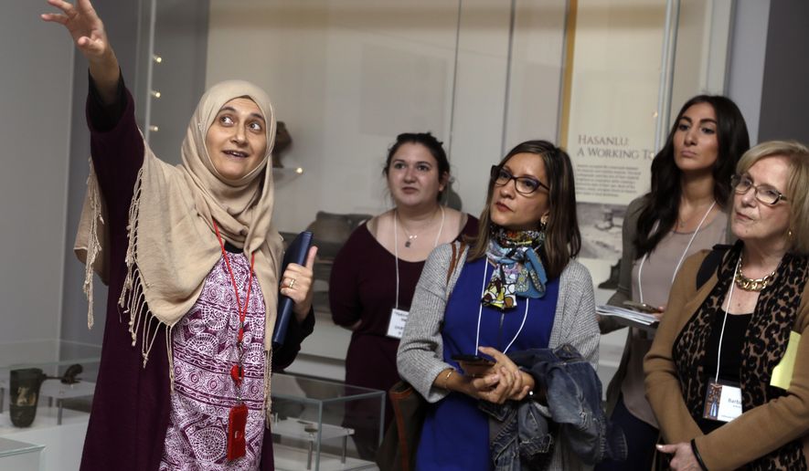 In this April 26, 2018 photo, Moumena Saradar, left, originally from Syria, guides visitors through the Middle East gallery at Penn Museum, in Philadelphia. The University of Pennsylvania Museum of Archaeology and Anthropology is in the midst of dramatic renovations, opening new galleries to showcase previously undisplayed items, telling the stories of those artifacts in more relatable ways and adding guides native to the parts of the world being showcased. (AP Photo/Jacqueline Larma)