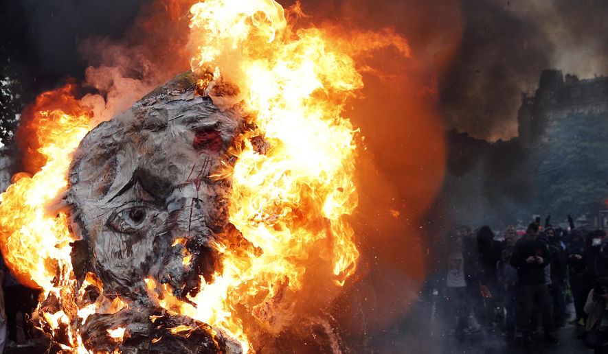 A giant mask depicting French President Emmanuel Macron is burned during a demonstration in Paris, Tuesday, May 22, 2018. French public services workers have gone on strike as part of their protest a government plan to cut 120,000 jobs by 2022. (AP Photo/Christophe Ena)