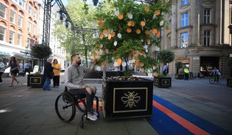 Martin Hibbertt, who suffered life-changing injuries in the Manchester terror attack, reads messages left on a &#39;Tree of Hope&#39; in St Ann&#39;s Square, Manchester, England ahead of the Manchester Arena National Service of Commemoration at Manchester Cathedral to mark one year since the attack, Tuesday May 22, 2018. (Peter Byrne/PA via AP)