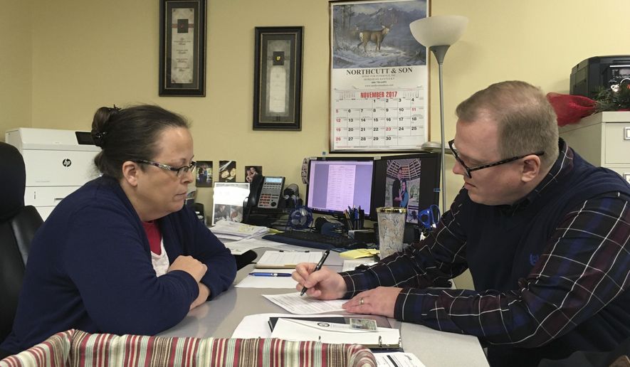 FILE - In this Dec. 6, 2017, file photo, David Ermold, right, files to run for Rowan County Clerk in Kentucky as Clerk Kim Davis look on in Morehead, Ky. Ermold, a gay man in Kentucky, wants to run against the county clerk who denied him a marriage license in 2015. But before Ermold can face Davis at the ballot box, he must first survive a four-person Democratic primary on Tuesday, May 22, 2018. (AP Photo/Adam Beam, File)