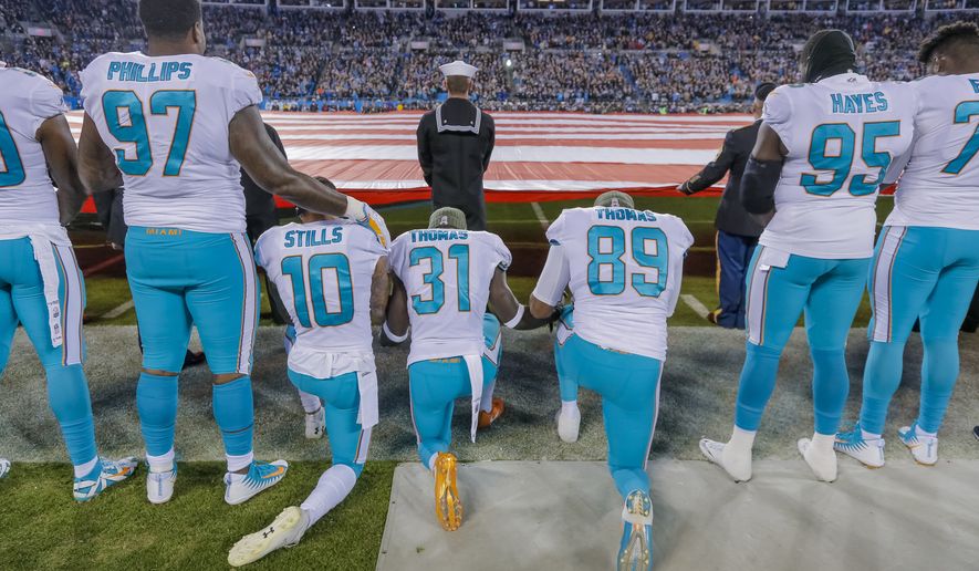Miami Dolphins&#x27; Jordan Phillips (97) stands during the national anthem, but shows support for the protest as he puts an arm on the shoulder of kneeling teammate, Kenny Stills (10), Michael Thomas (31) and Julius Thomas (89) before an NFL football game against the Carolina Panthers in Charlotte, N.C., Monday, Nov. 13, 2017. The Panthers won 45-21. (AP Photo/Bob Leverone)