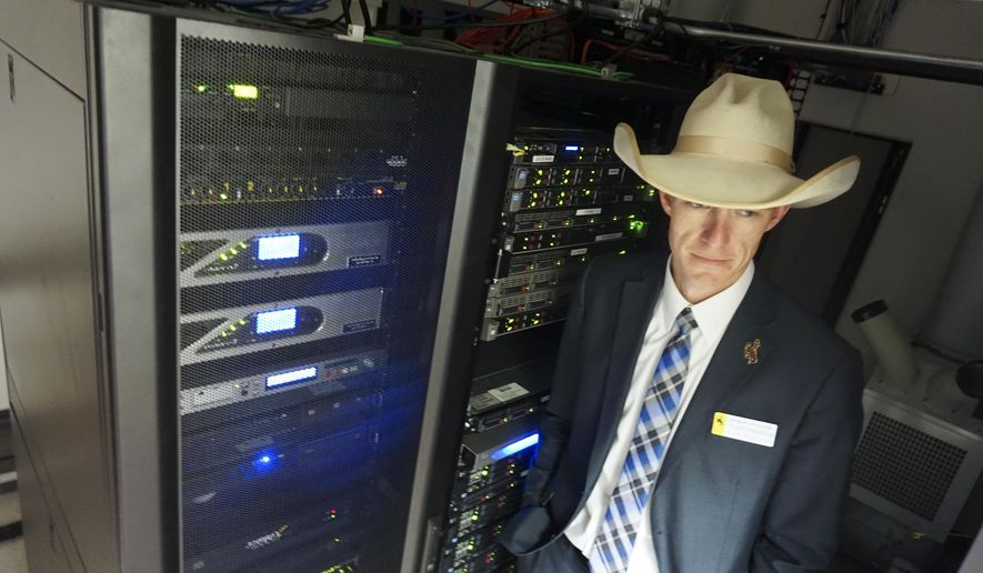 In this March 8, 2018, photo Wyoming state Rep. Tyler Lindholm poses next to computer servers in an office building in Cheyenne, Wyo. Lindholm was a lead proponent of several new laws that have made Wyoming friendly to the networked ledgering technology called blockchain. Supporters say that by welcoming blockchain, the technology underlying cryptocurrencies including bitcoin, Wyoming has become a good place for tech business. (AP Photo/Mead Gruver)
