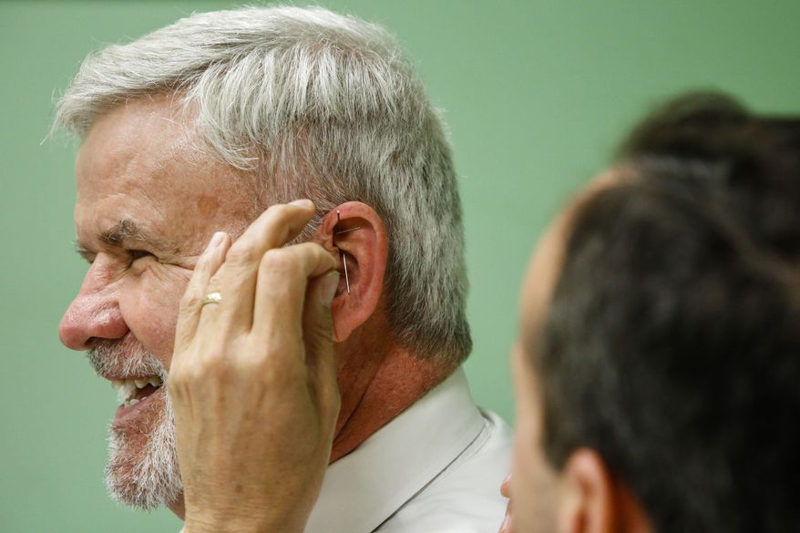 In this photo taken May 9, 2018, Pickaway County Court of Common Pleas Judge P. Randall Knece, laughs as Dr. Kenneth J. Laux, right, places needles in his ear during an acupuncture treatment at Pickaway Area Recovery Services in Circleville, Ohio. With the help of grant money, Dr. Laux began using acupuncture as a way to help treat people recovering from opioid disorder. Judge Knece decided to sit in and receive the treatment in a show of support to the people in recovery at the session. (Joshua A. Bickel/The Columbus Dispatch via AP)