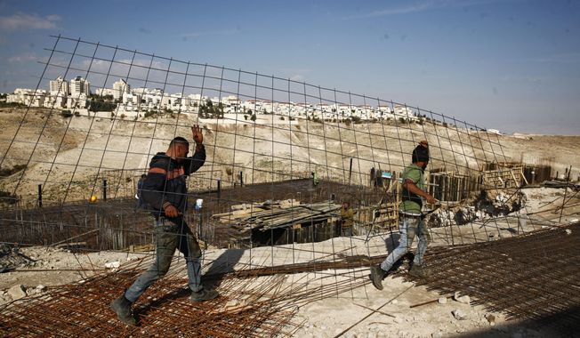 FILE - In this Jan. 22, 2017 file photo, workers carry material at a construction site in the West Bank settlement of Maaleh Adumim. Israeli Defense Minister Avigdor Lieberman said Thursday, May 24, 2018, that he will seek approval next week to fast-track construction of 2,500 new West Bank settlement homes this year and advance 1,400 more units that are currently in the planning stage. Senior Palestinian official Hanan Ashrawi condemned Lieberman’s announcement as “Israeli colonialism, expansionism and lawlessness” and called on the International Criminal Court in The Hague, Netherlands, to launch an investigation. (AP Photo/Mahmoud Illean, File)