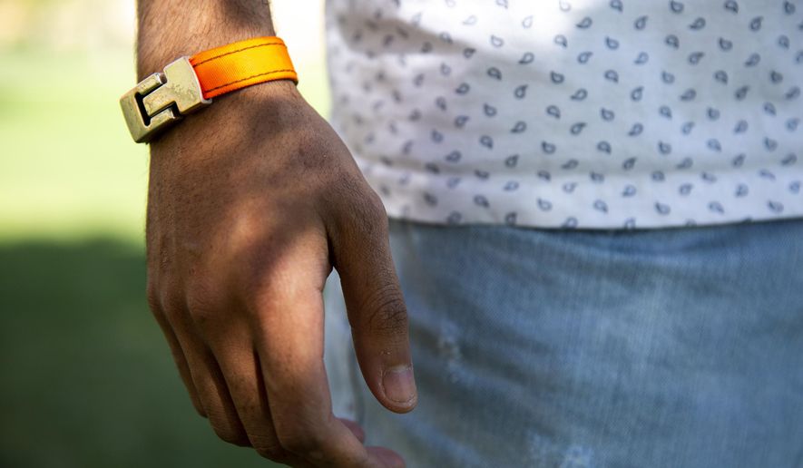 Mohamed Malim models a bracelet made from recycled lifejackets worn by refugees crossing the Mediterranean sea and the first piece he&#x27;s designed for his fashion brand, Epimonia, on the University of St. Thomas campus in St. Paul, Minn., on Tuesday, May 15, 2018. Malim, a senior at St. Thomas, came to the US from Somalia as a refugee in the 90s. (Evan Frost/Minnesota Public Radio via AP)
