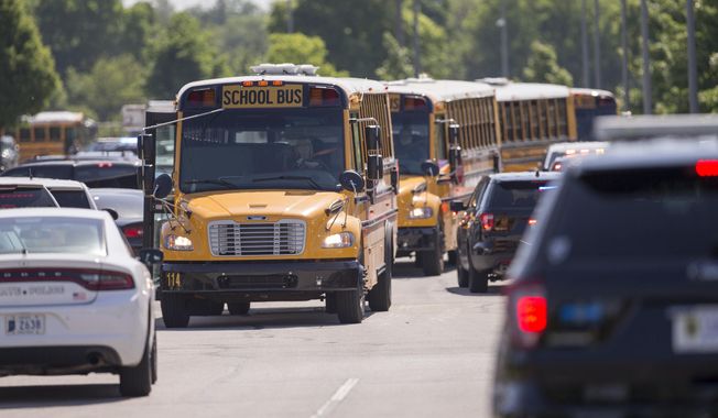 Empty school buses leave after a shooting at Noblesville West Middle School in Noblesville, Ind., on Friday, May 25, 2018. A male student opened fire at the suburban Indianapolis school wounding another student and a teacher before being taken into custody, authorities said. (Robert Scheer/The Indianapolis Star via AP)
