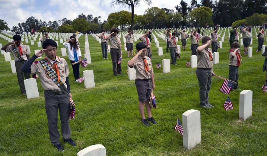 Boy Scout troop 10 from the Reseda section of Los Angeles offers a salute at the Los Angeles National Cemetery in Los Angeles on Saturday, May 26, 2018. More than 6,000 scouts, with the support of local community members, placed 88,000 American flags on graves throughout the cemetery to honor fallen service members in anticipation of Memorial Day. (AP Photo/Richard Vogel)