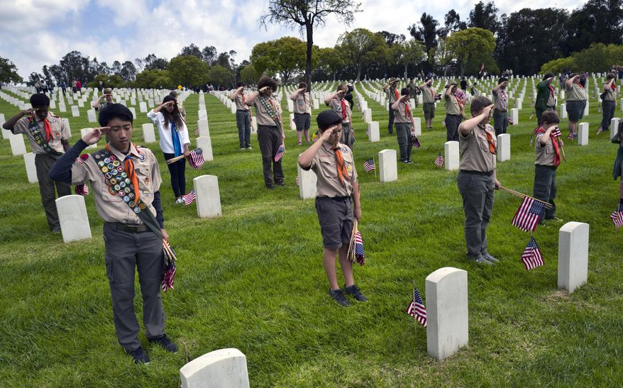 Boy Scout troop 10 from the Reseda section of Los Angeles offers a salute at the Los Angeles National Cemetery in Los Angeles on Saturday, May 26, 2018. More than 6,000 scouts, with the support of local community members, placed 88,000 American flags on graves throughout the cemetery to honor fallen service members in anticipation of Memorial Day. (AP Photo/Richard Vogel)